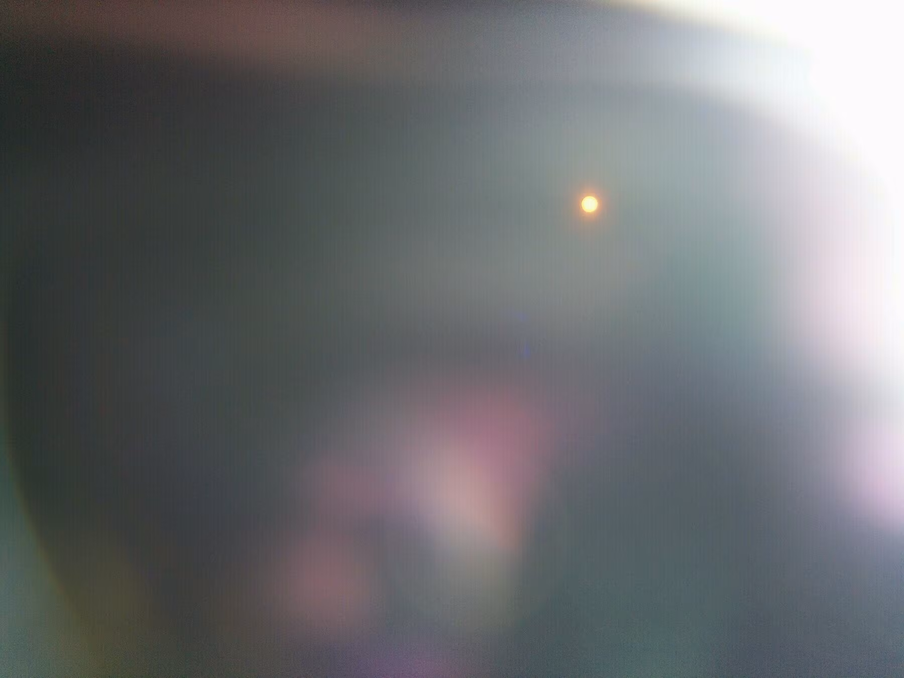A blurry image with soft gradients of color and a small, bright orange dot in the corner.