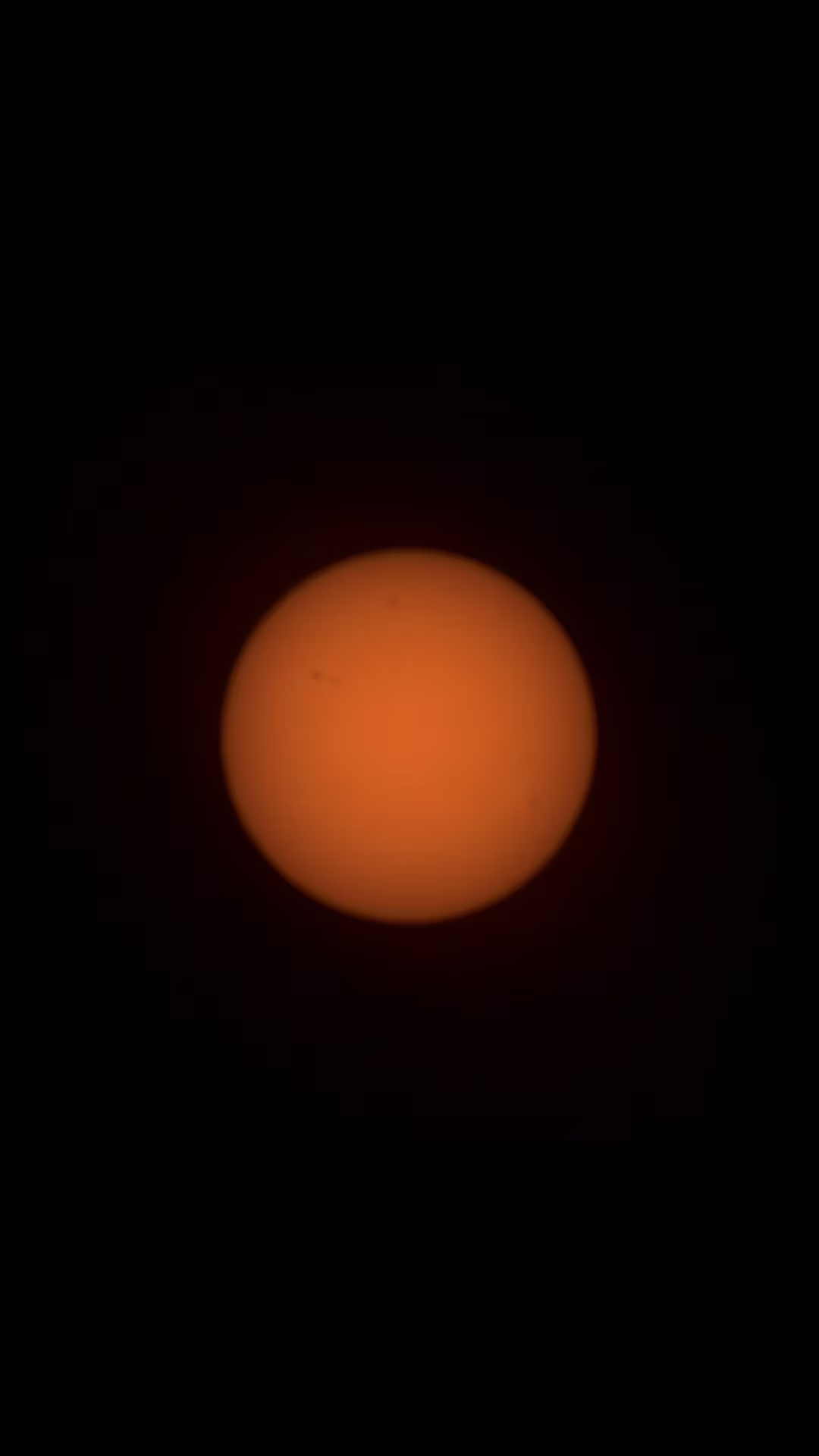 A close-up image of the sun showing a detailed and textured orange surface surrounded by darkness, highlighting sunspots and solar features.
