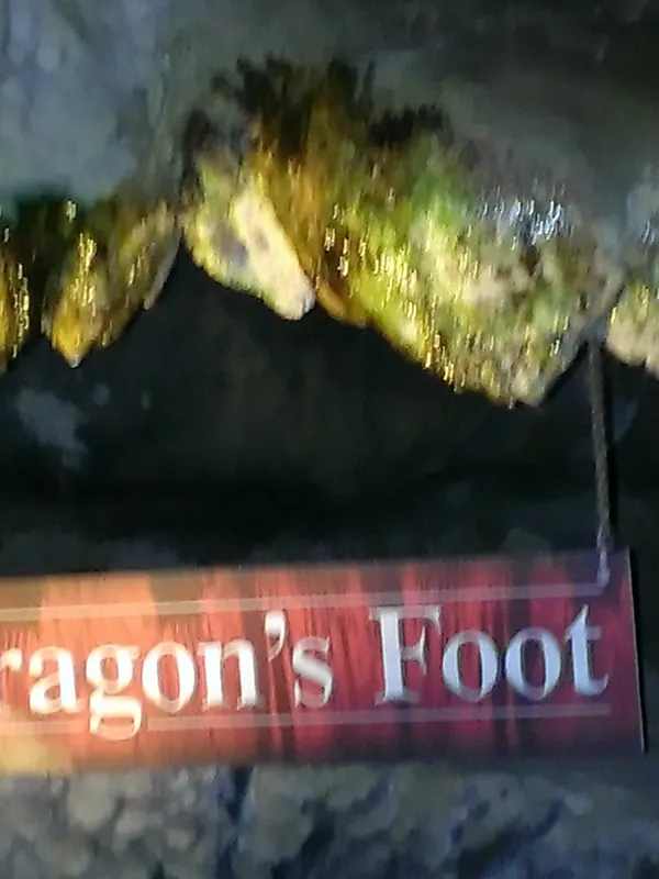 Green-lit stalactite formation with a Dragon's Foot sign