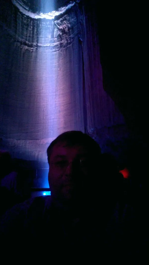 Portrait in the waterfall chamber with deep blue and purple cave lighting