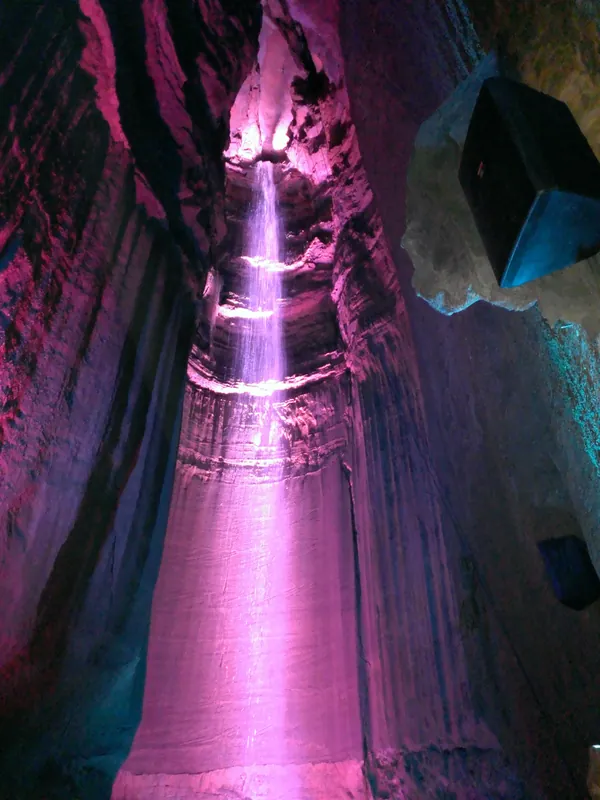Ruby Falls cascading down the cave wall, lit in vivid pink and purple