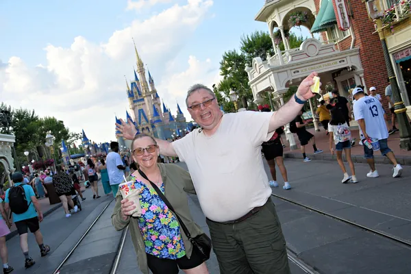 Two people celebrating on Main Street USA with Cinderella Castle in the background