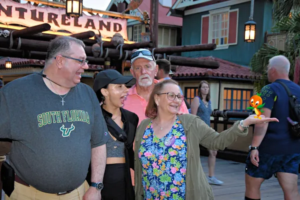 Four people in Adventureland, one holding a small Orange Bird figure on her hand